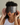 Woman wearing a dark gray ZILK silk Deep Restoration sleep mask over her eyes while sitting in bed. 