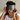Woman wearing a dark gray ZILK silk Deep Restoration sleep mask over her eyes while sitting in bed. 
