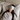 Woman wearing a light gray ZILK silk sleep mask over her eyes laying in bed with her head on a white silk pillowcase.