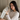 Woman holding a dark gray silk sleep mask in her hands to show the soft, pillowy feel while sitting in a bed.