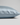A close-up of a pillowcase in light blue silk, showing its smooth texture and hidden zipper detail, set against a neutral light gray background.