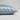 A close-up of a pillowcase in light blue silk, showing its smooth texture and hidden zipper detail, set against a neutral light gray background.