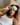 woman wearing a light gray silk sleep mask on her forehead laying in bed on a  pink silk pillowcase