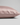 A close-up of a pillowcase in light pink silk, showing its smooth texture and hidden zipper detail, set against a neutral light gray background.