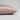 A close-up of a pillowcase in light pink silk, showing its smooth texture and hidden zipper detail, set against a neutral light gray background.