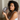 woman with curly hair holding a dark gray silk sleep mask showing the sculpted eye contours that protect eyelashes